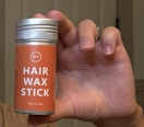 a hand holding a hair wax stick