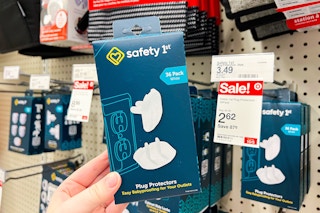 hand holding a pack of safety 1st plug protectors in front of Target sale tag