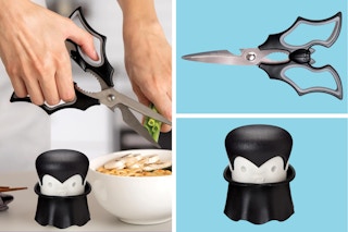 Hands cutting green onions with the Elizabat kitchen scissors while Gracula garlic crusher looks on. Elizabat and Gracula on blue