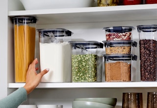 hand reaching for a clear container in a pantry 