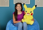 child sitting on a bean bag chair holding the Pikachu plush