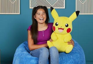 child sitting on a bean bag chair holding the Pikachu plush