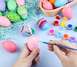 a person painting an Easter egg pink