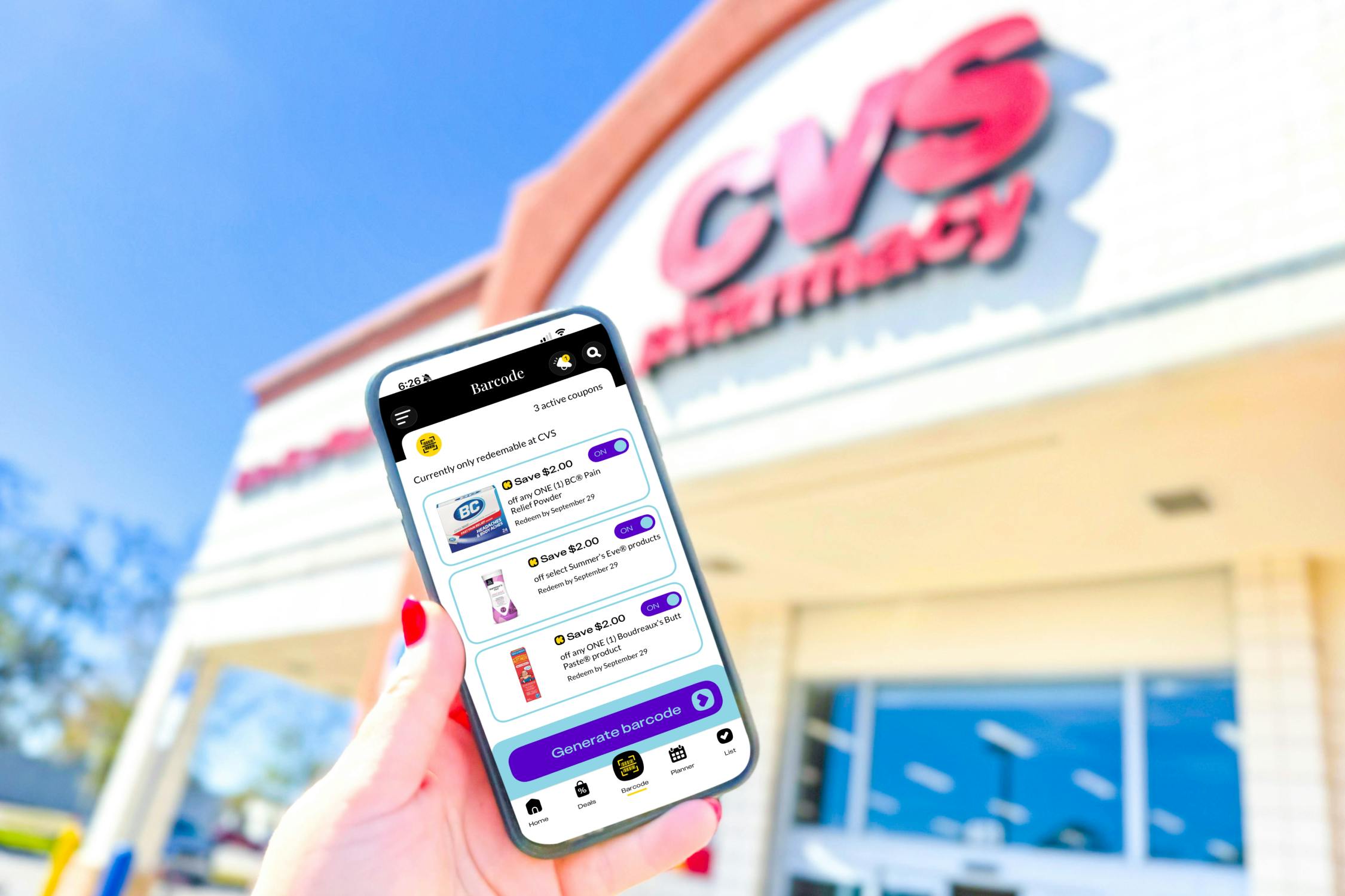 hand holding a smartphone in front of a CVS store displaying KCL coupons