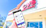 hand holding a smartphone in front of a CVS store displaying KCL coupons