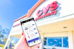 hand holding a smartphone in front of a CVS store displaying KCL coupons