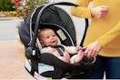 Woman holding a Graco Car Seat with an infant in it.