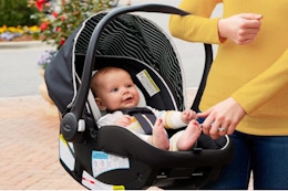 Woman holding a Graco Car Seat with an infant in it.