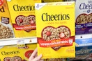 hand holding a box of cheerios cereal
