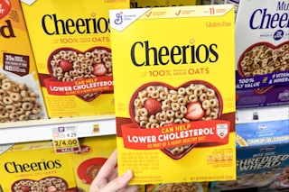 hand holding a box of cheerios cereal