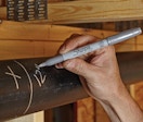 a person writing on a pipe with a metallic marker