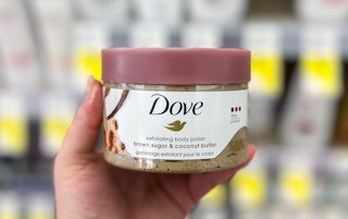 a hand holding a jar of body scrub 