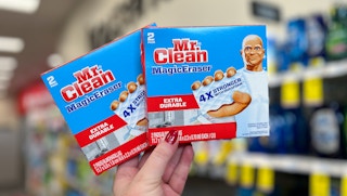 person holding two Mr. Clean magic eraser boxes