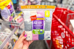 hand holding a pack of hanes kids' underwear in front of a target cart