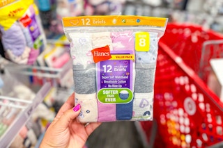 hand holding a pack of hanes kids' underwear in front of a target cart