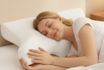 woman laying in bed on a cervical pillow