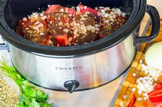 a crockpot sitting on a counter cooking meat 