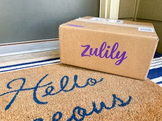 A Zulily box sitting on a front porch in front of someone's front door.