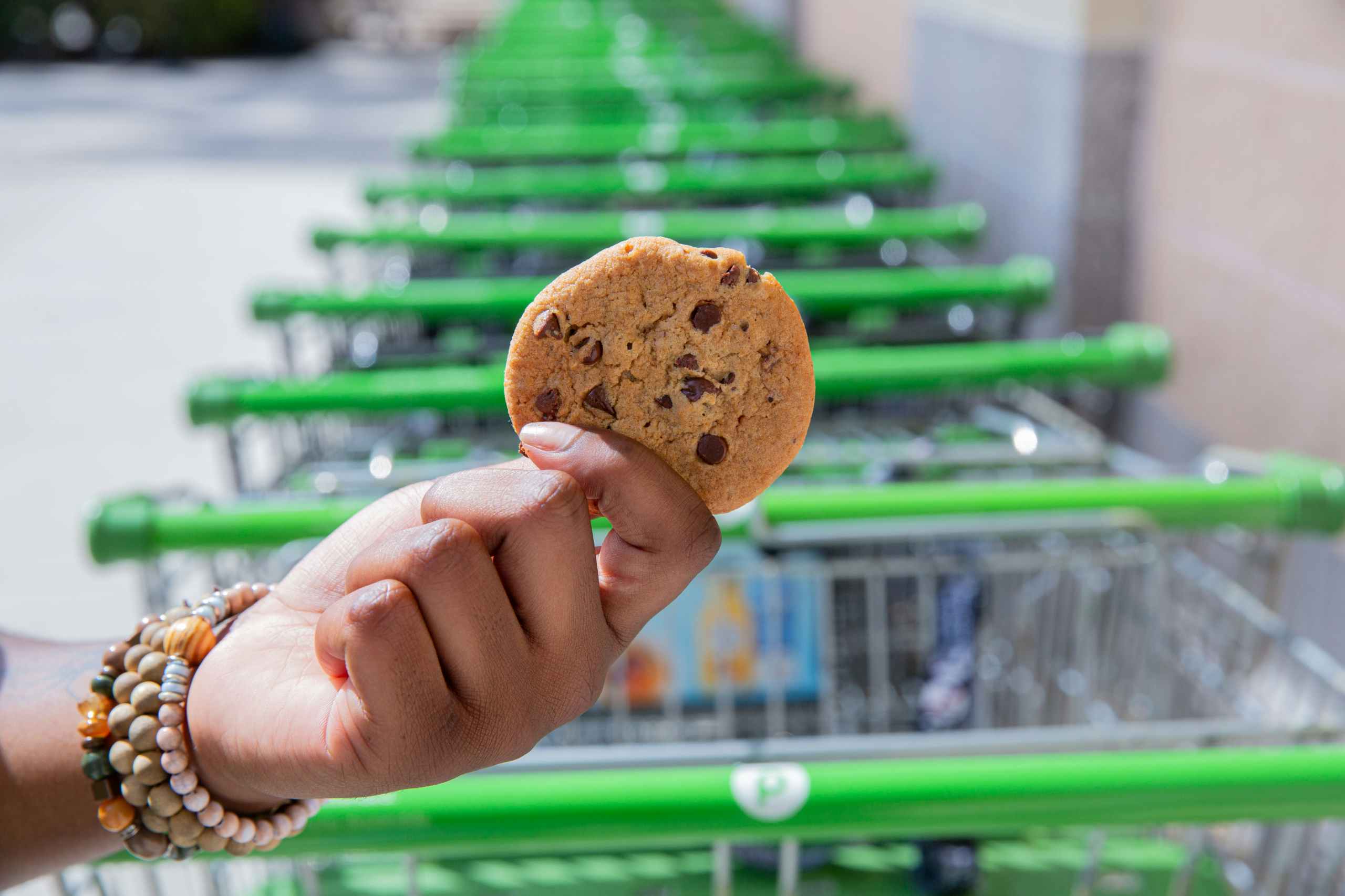 someone holding up a cookie by some Publix carts