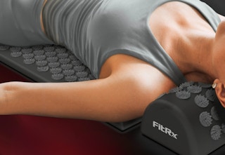 personal laying on a black accupressure mat and pillow