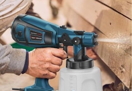 a person using a paint sprayer on wooden panels