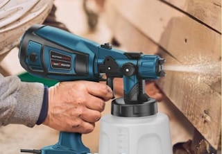 a person using a paint sprayer on wooden panels