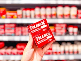 hand holding two boxes of tylenol caplets in walmart aisle