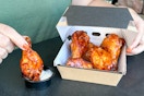 someone eating chicken wings from a box
