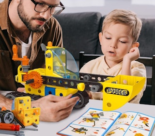 a dad and son building a toy on a table
