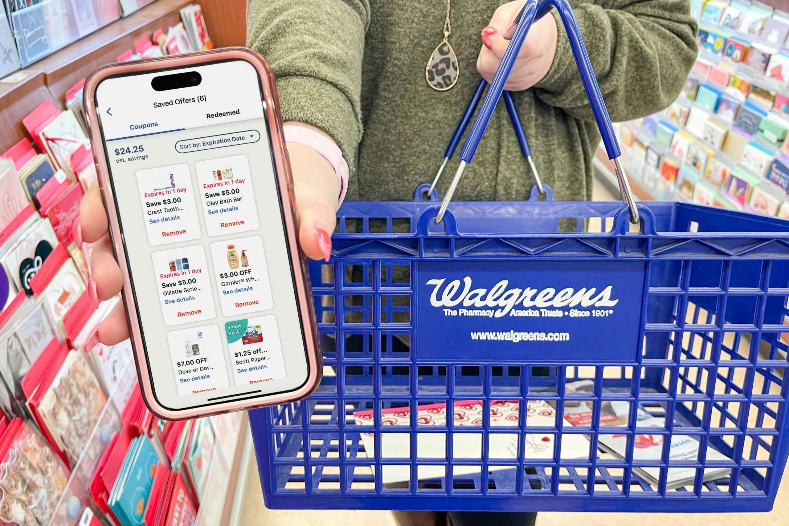 Someone holding a phone displaying the coupons in the Walgreens app and holding a Walgreens shopping basket