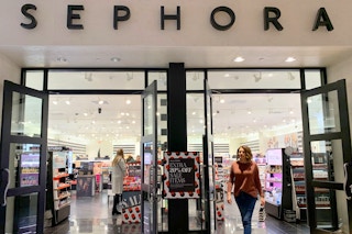 Woman walking out of Sephora store with shopping bag.