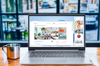 Lifestyle image of the Lenovo IdeaPad Laptop on wooden table with mug in front of window