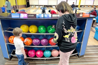 two kids looking at bowling balls to pick one out