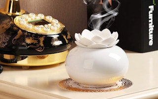 a white ceramic lotus flower essential oil diffuser on a table in front of an old fashioned phone
