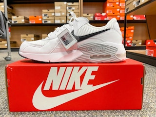 A white Nike Air Max shoe sitting atop a Nike shoe box in the middle of a store aisle.