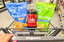 person pushing a cart with a 2-liter of soda and 2 bags of chips