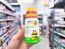 hand holding a bottle of zarbees cough syrup in walmart aisle