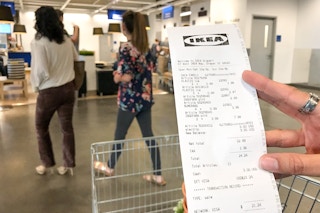 someone holding a costco receipt in front of a cart