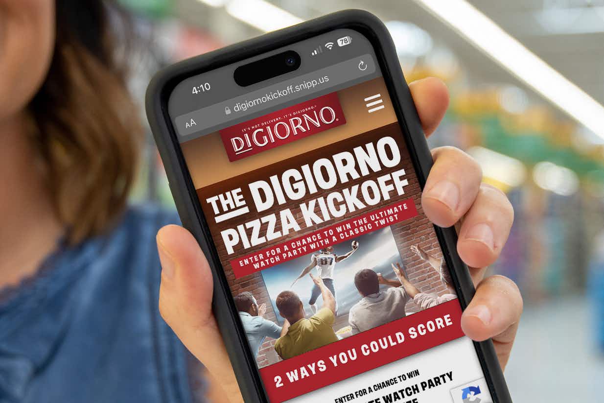 someone holding up a phone showing the digiorno pizza kickoff website