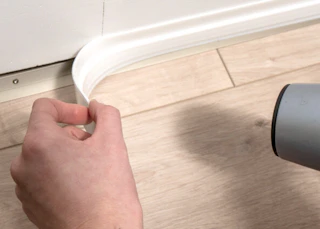 a person putting a draft stopper at the bottom of a door