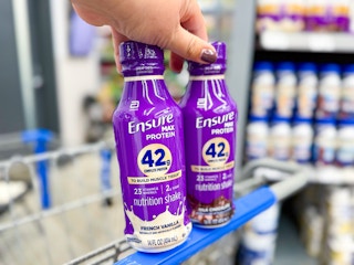 hand holding Ensure Max Protein shakes - chocolate and vanilla