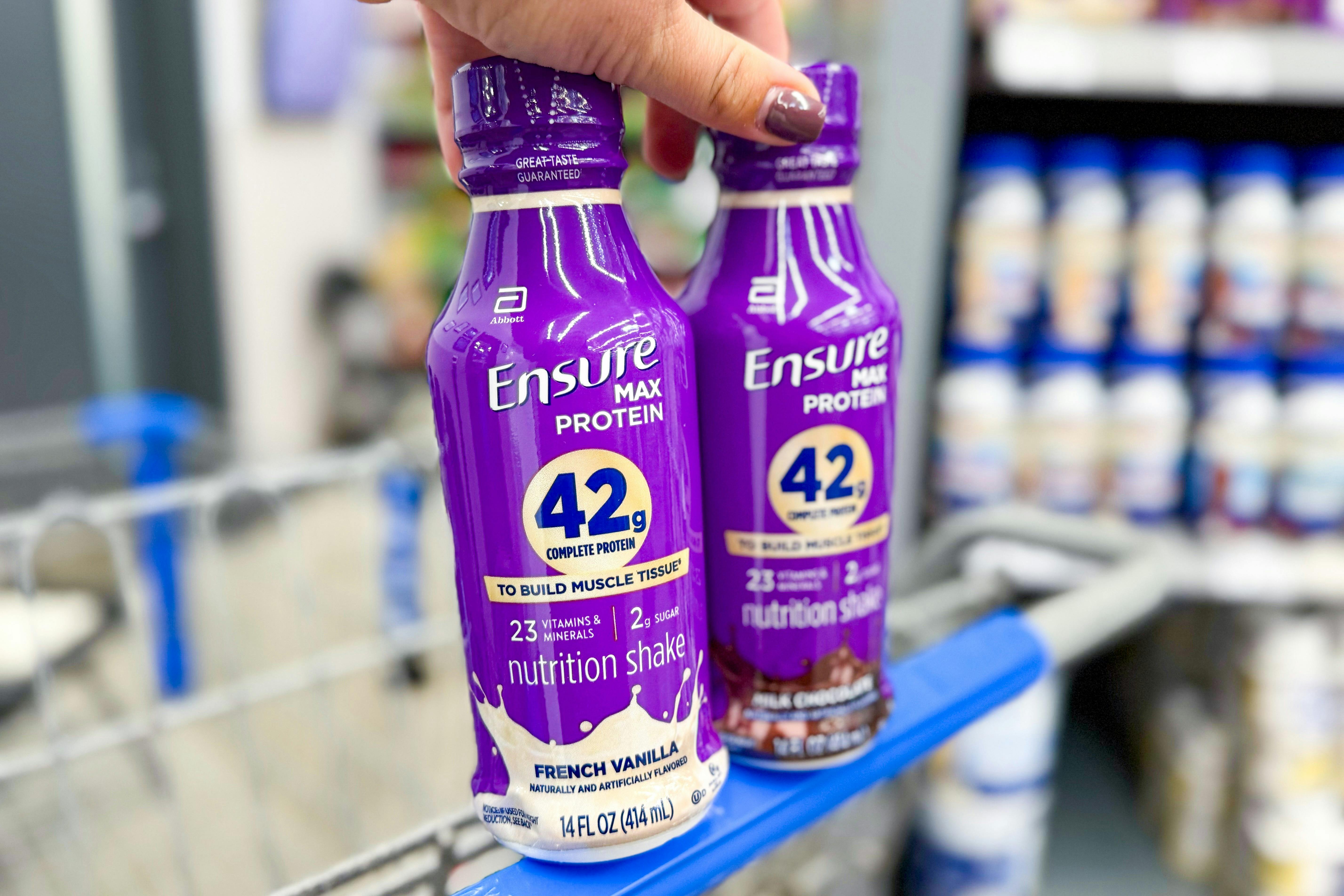 hand holding Ensure Max Protein shakes - chocolate and vanilla