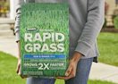 a person holding a bag of grass seed