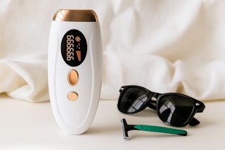 a woman using a laser hair removal device on her under arms 