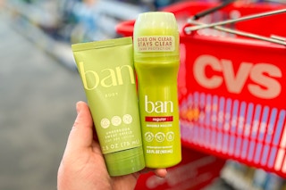 hand holding a tube and stick of ban deodorant in front of cvs shopping basket