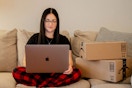 person on couch with laptop and amazon boxes