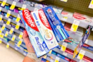 Hand holding Crest and Colgate toothpastes