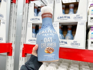 Someone holding a bottle of Califa Farms oat creamer on clearance at Sam's Club