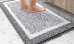 a person standing on a grey and white bathroom rug