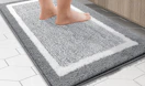 a person standing on a grey and white bathroom rug